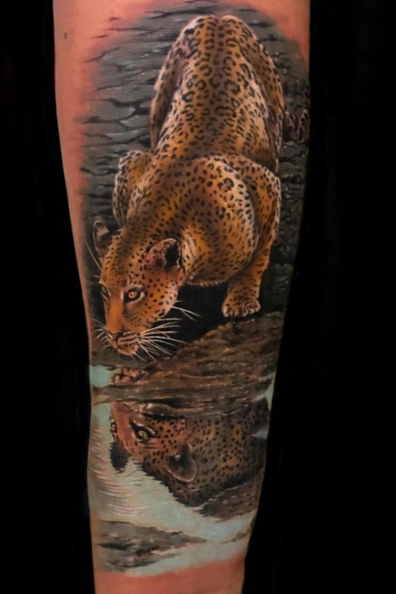 Tatuaje de Jaguar reflejandose en un charco